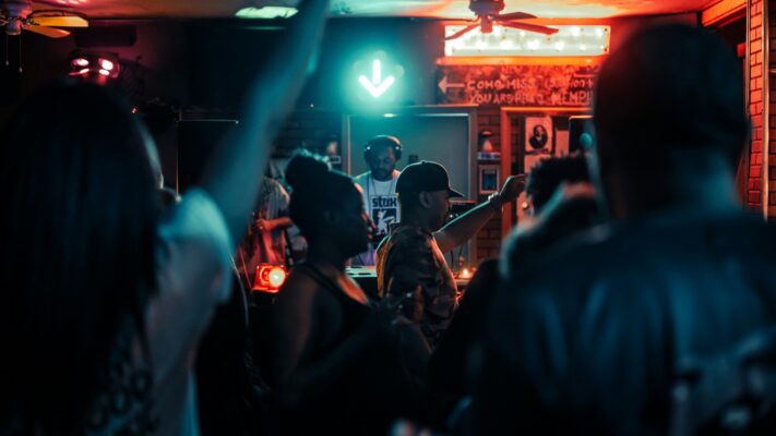 Dansende mensen op een feest met DJ en kleurrijke verlichting tijdens een feestavond thuis